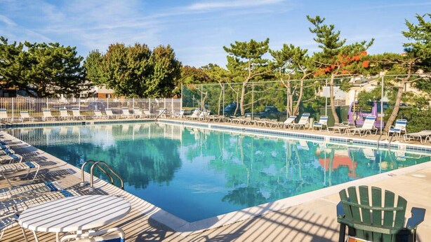 A rectangular swimming pool with clear blue water, surrounded by lounge chairs and a deck area. - Walk to the Beach or the Bay! (Ocean City)