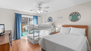 A hotel room with a bed, a desk, a computer, a ceiling fan, and a view of the outside. - Walk to the Beach or the Bay! (Ocean City)