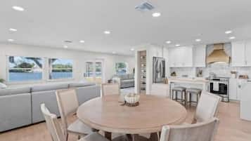 A modern kitchen with white cabinets, a round wooden table, and a built-in oven.