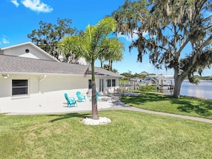 A house with a patio, a small tree, and a view of a lake. - Waterfront Experience | Boatlift & Boat Rental (Tarpon Springs)