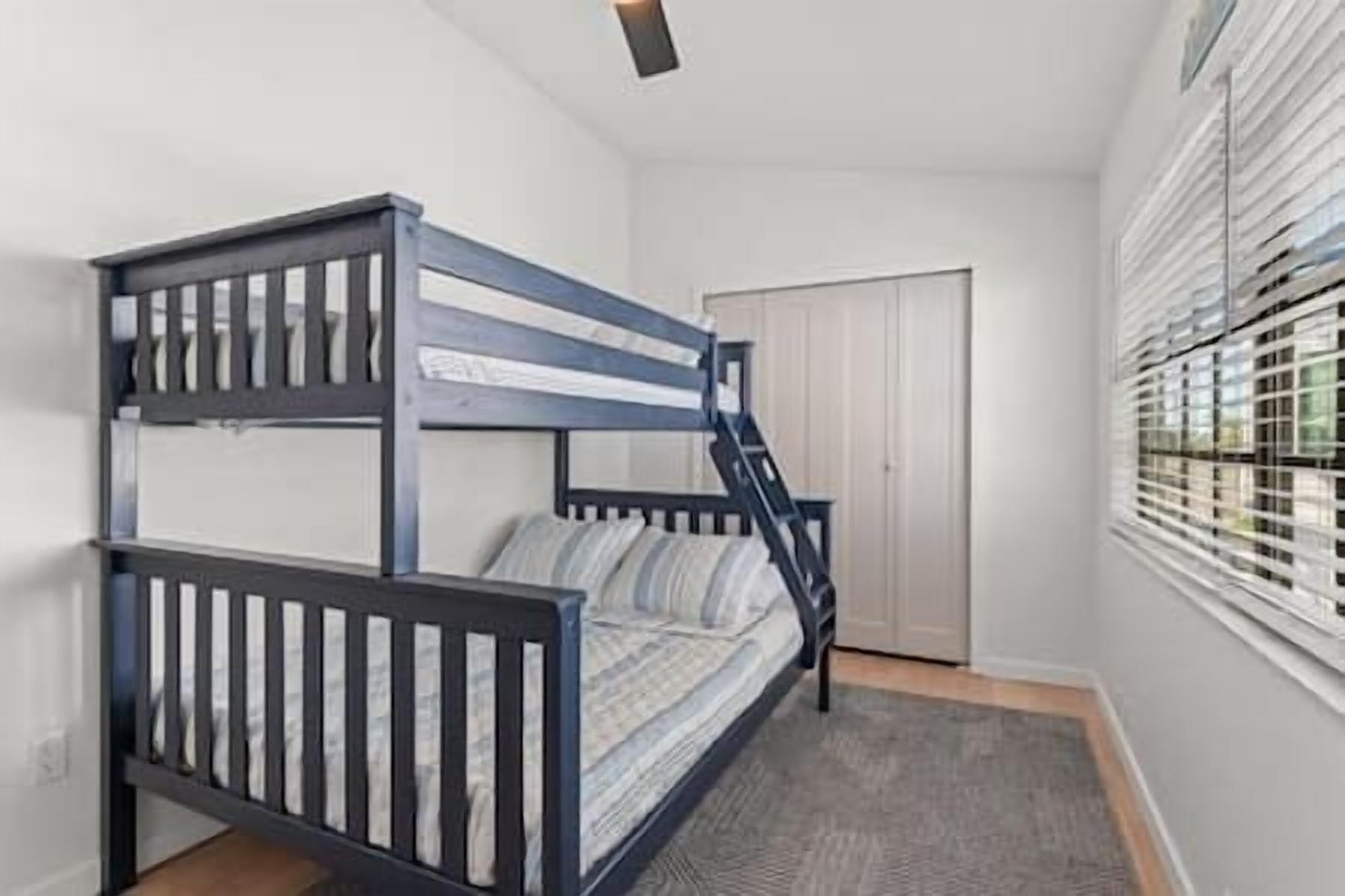 Ein Stockbett in einem Zimmer mit Fenster und Tür.