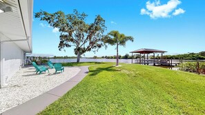 A grassy area with a gazebo, chairs, and a lake view. - Waterfront Experience | Boatlift & Boat Rental (Tarpon Springs)