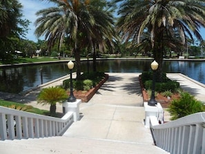 A pathway leading to a body of water with palm trees and lamp posts. - Waterfront Experience | Boatlift & Boat Rental (Tarpon Springs)