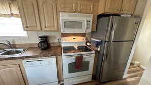 Une cuisine compacte équipée d’un four à micro-ondes, d’une cuisinière, d’un réfrigérateur et d’un lave-vaisselle.