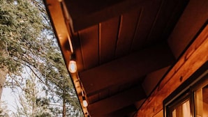 Eine Holzhütte mit überdachter Veranda, Grill und Bank.
