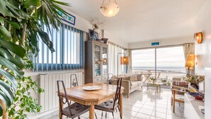 Un vaste espace de vie comprenant une table à manger, des chaises, un canapé et une vue sur l’océan.