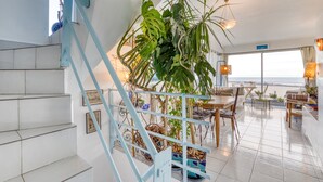 Un vaste espace de vie comprenant un escalier, un coin repas et une vue sur l’océan.