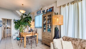 Un salon comprenant un canapé, une table à manger avec des chaises, un meuble et une grande plante.