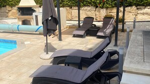 Ein Poolbereich mit Liegestühlen und einem Grill.