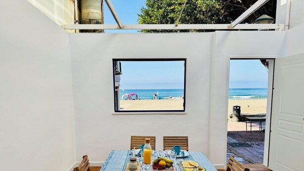 En matplats med ett bord dukat för frukost, med utsikt över en strand.