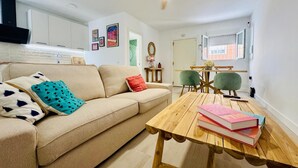 Ett modernt vardagsrum med en beige soffa, ett träbord och en matplats med ett litet bord och stolar.
