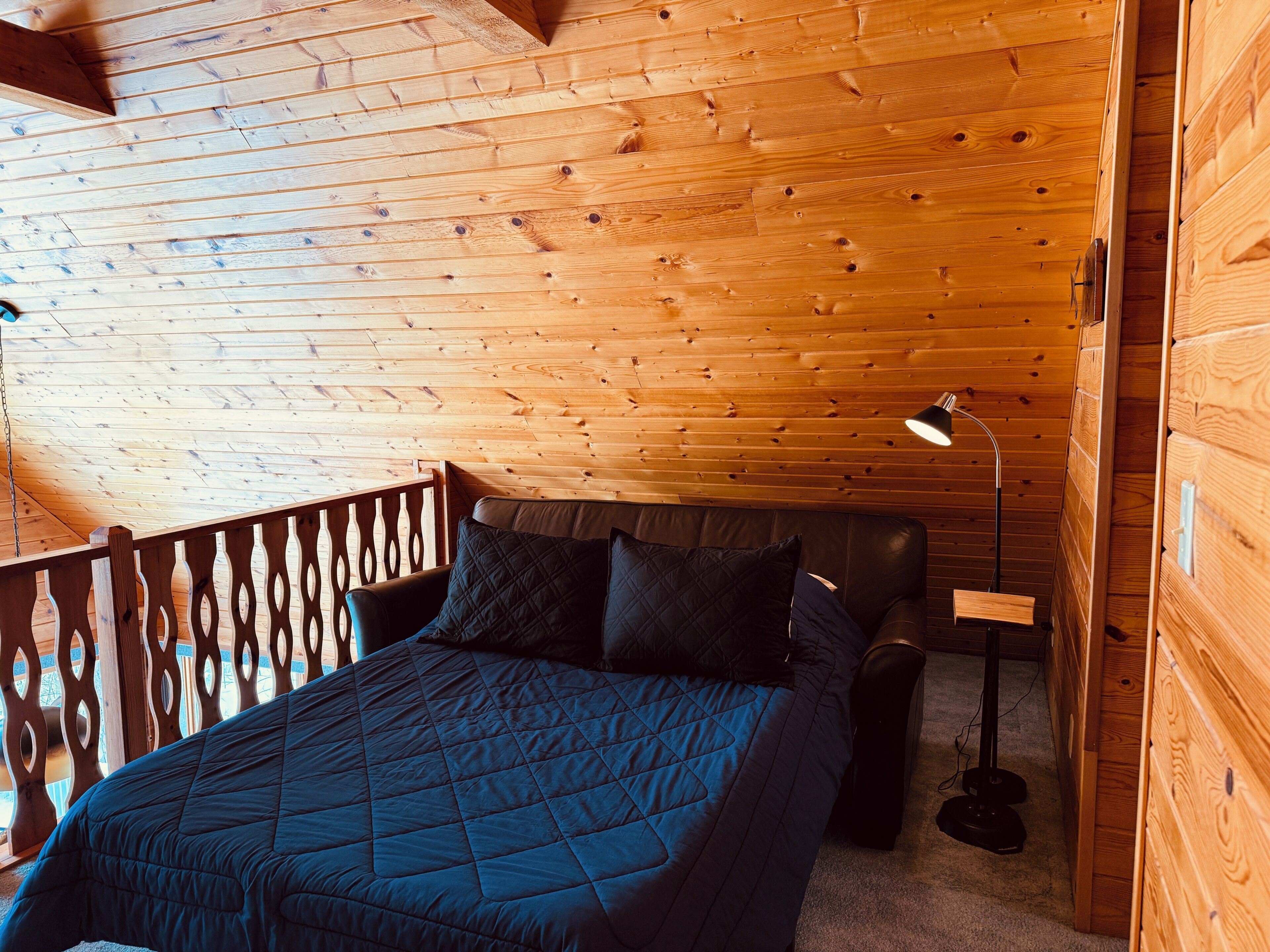 A wooden-paneled room with a bed, a desk, and a chair.