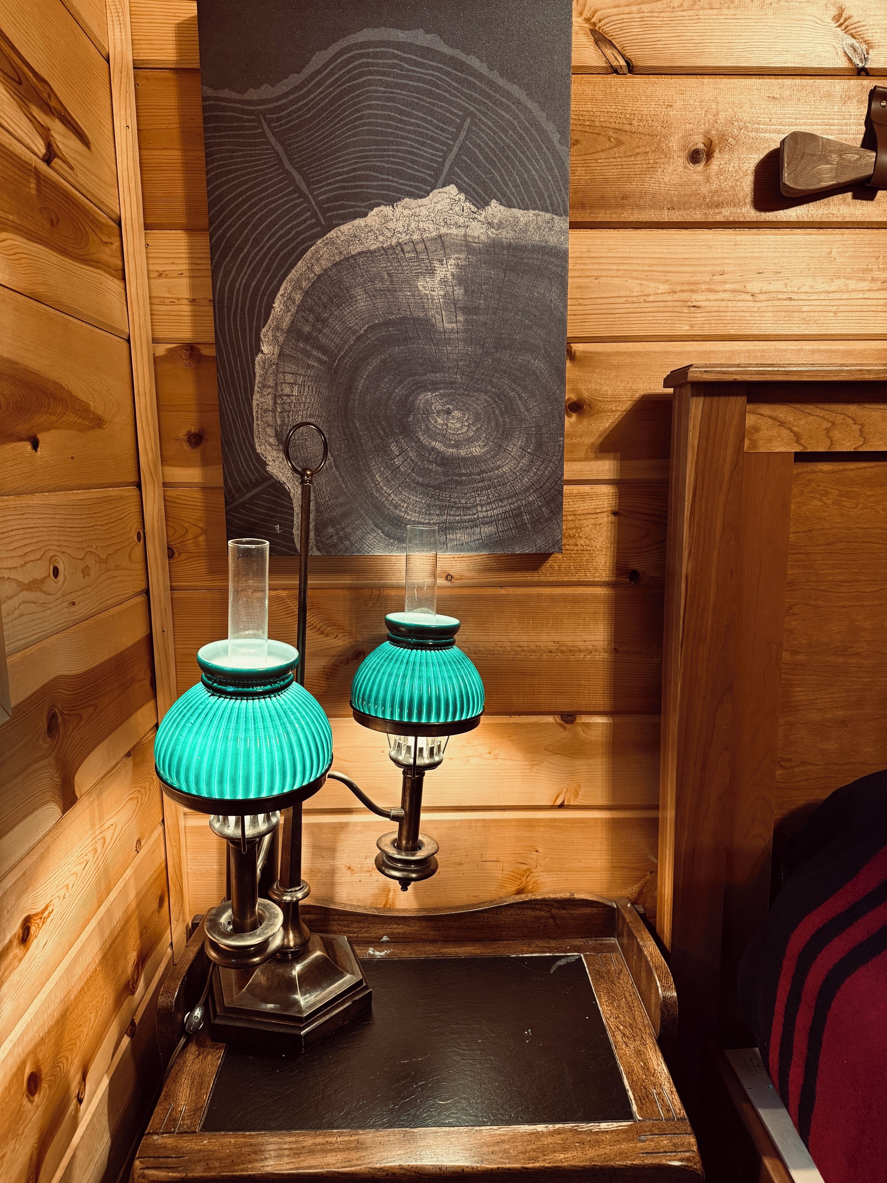 Een houten interieur met twee teal lampen op een zwarte tafel, een houten wand met een rond ontwerp en een houten deur.