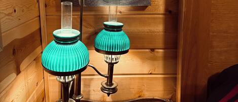 Een houten interieur met twee teal lampen op een zwarte tafel, een houten wand met een rond ontwerp en een houten deur.