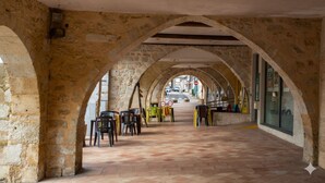 An arched stone corridor with chairs and tables, leading to a street view. - Gîte des 3 Moulins - A haven of tranquillity in the heart of the vineyards (Gornac)