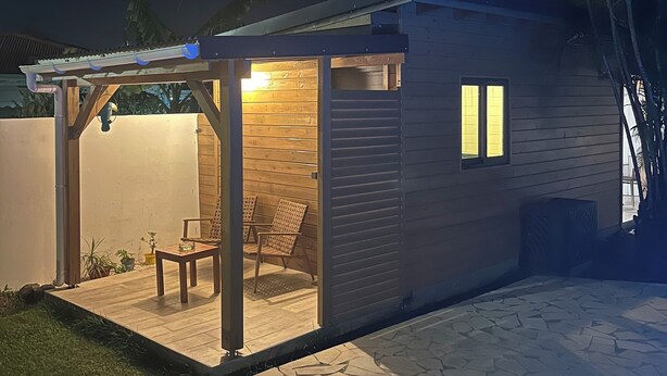 A modern outdoor patio area with a wooden pergola, two chairs, and a small table. - Coco Banana - Superior bungalow - pool view (Baie-Mahault)