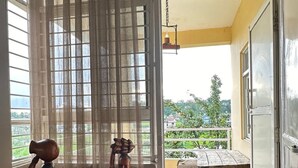 A room with a sliding glass door leading to a balcony with a wooden table and chairs. There are three wooden statues on the wall.