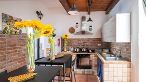 Uma cozinha com parede de tijolos, bancada preta, pia e fogão.