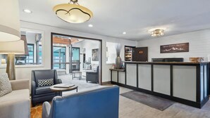 Eine moderne Hotelhalle mit Rezeption, Sitzgelegenheiten und Blick ins Freie.