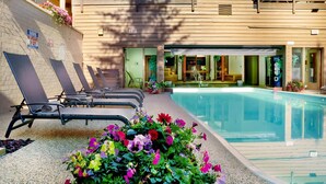 Ein Poolbereich mit Liegestühlen, einem Pool und einem Gebäudeeingang.