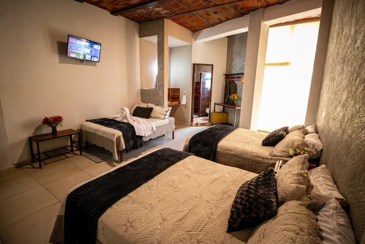 Habitación de hotel con dos camas, un televisor en la pared y vistas al exterior.