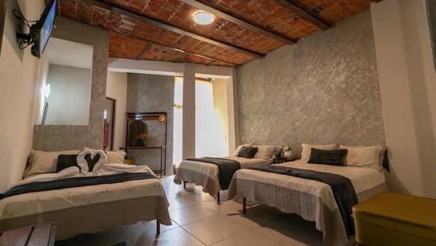 Habitación de hotel con dos camas individuales, techo de ladrillo y un espejo grande.