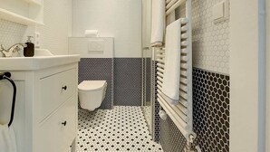 A bathroom with a white sink, toilet, and towel rack. - 1-bedroom apartment with glass roof, city center (Luxembourg)
