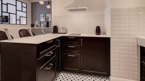 A modern kitchen with dark cabinetry, a white countertop, and a tiled backsplash. - 1-bedroom apartment with glass roof, city center (Luxembourg)