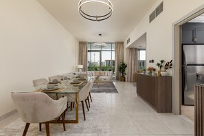 A modern dining area with a glass table, cushioned chairs, and a contemporary chandelier. - Spacious 3BD Family Home w Maid s Room in Meydan (Dubai)