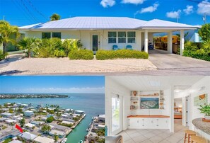 A coastal house with a covered porch, a view of the sea, and a spacious kitchen with white cabinets and a wooden countertop. - Florida Keys Coastal Retreat (Marathon)