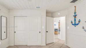 Una habitación con dos camas, paredes de madera blanca y un pasillo que conduce a otra habitación.