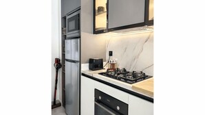 Een moderne keuken met een ingebouwde oven, magnetron en gasfornuis.