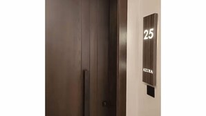 Een gesloten liftdeur met het cijfer '25' en de tekst 'AZURA' op de muur ernaast.
