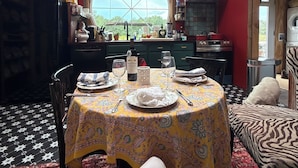 A dining area with a table set for two, a large window, and a view of the outdoors.