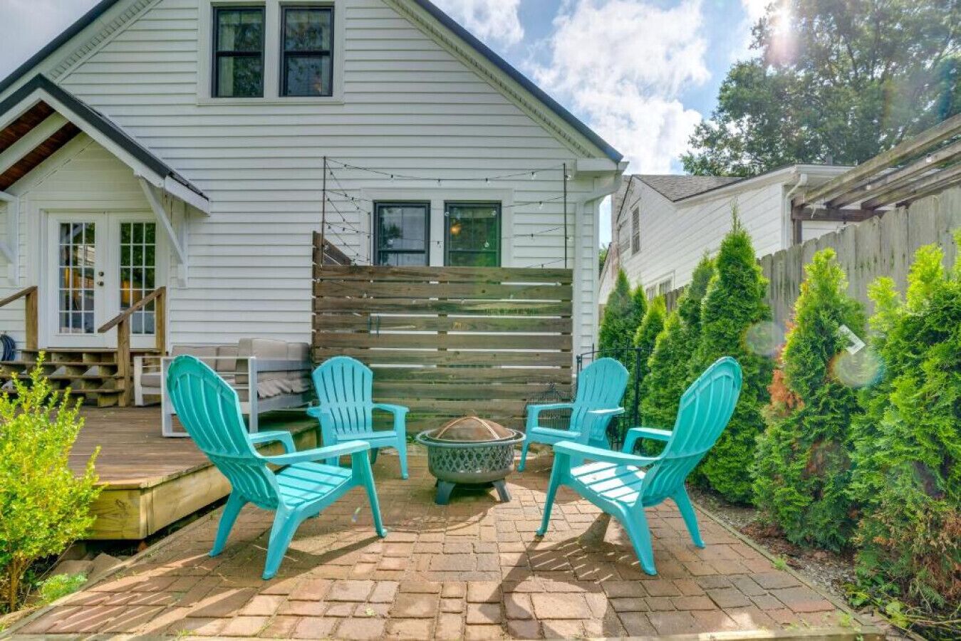 Eine Terrasse mit vier türkisfarbenen Adirondack-Stühlen, einer Feuerstelle und einem Holzboden.