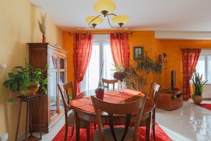 Un coin repas comprenant une table ronde, des chaises, un lustre et un buffet.