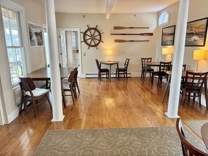 A dining area with wooden flooring, white pillars, and a ship's wheel on the wall. - Large Home Southwest Harbor overlooking the Harbor (Southwest Harbor)
