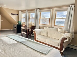 Una habitación de hotel con cama, sofá, mesa de comedor y refrigerador.