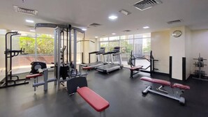 Et fitnesscenter med forskellig træningsudstyr, store vinduer og en bænk.