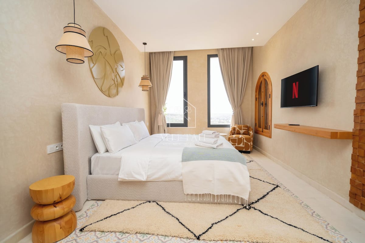Un dormitorio moderno con una cama grande, un televisor y vistas de la ciudad.