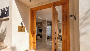 L’entrée d’un hôtel, avec une porte en bois, un escalier et une enseigne indiquant « BAR LAZIZA ».