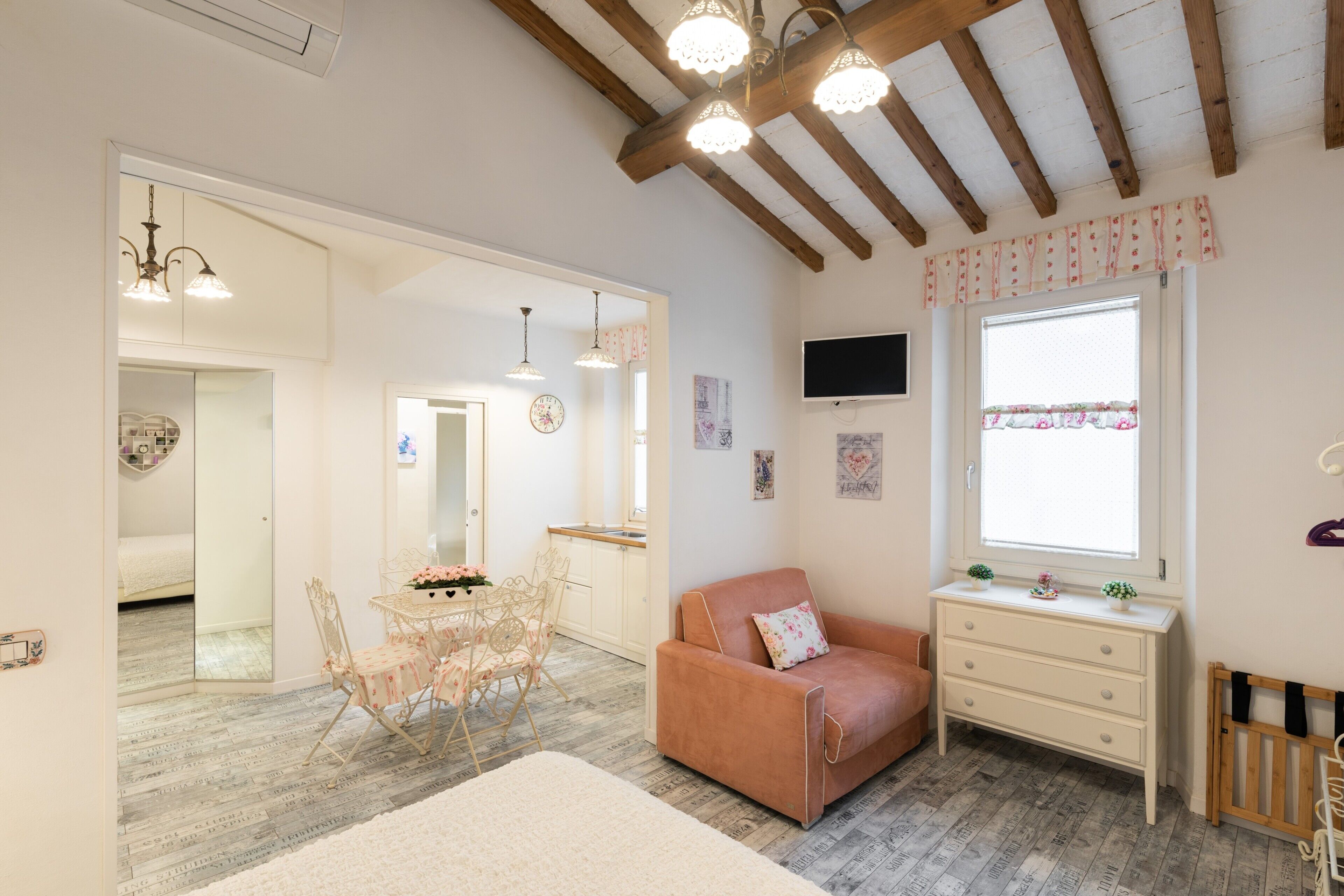 A cozy room with a wooden ceiling, a sofa, a small table, and a TV on the wall.