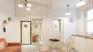 Una habitación acogedora con sofá, una mesa de comedor con sillas, una zona de cocina y un pasillo que lleva a otra habitación.