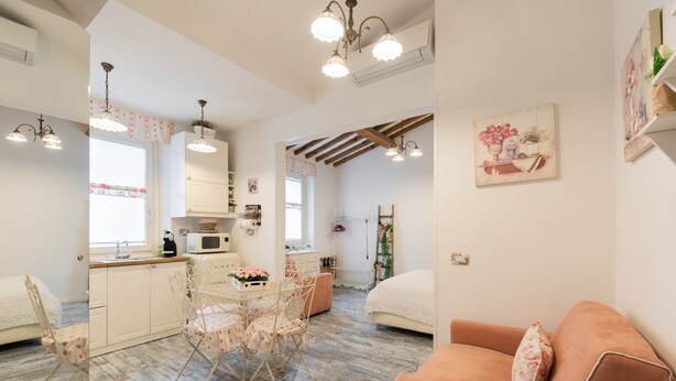 Una habitación acogedora con cama, sofá, mesa de comedor con sillas y zona de cocina.