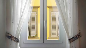 A room with two windows, each with shutters, and sheer curtains. - Casa Ornella – Charm on Two Levels in the Heart of Florence (Firenze FI)