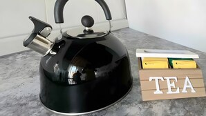A black kettle on a marble countertop next to a wooden box labeled 'TEA'. - Casa Ornella – Charm on Two Levels in the Heart of Florence (Firenze FI)