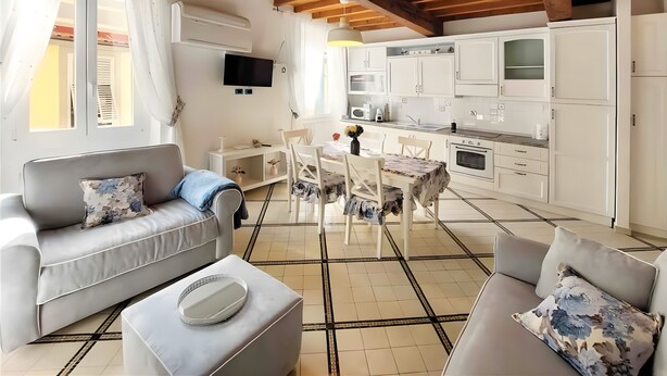 A modern living room with a sofa, ottoman, and a dining table with chairs. - Casa Ornella – Charm on Two Levels in the Heart of Florence (Firenze FI)