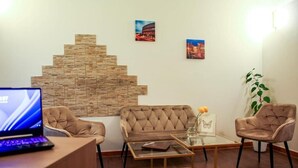 A modern living area with a sofa, two armchairs, a glass coffee table, and a laptop on a wooden desk. - Farfalla Bianca - Rooms (Rome)
