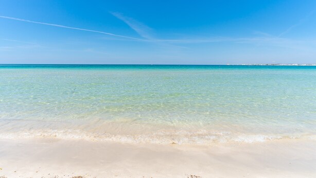 Een strand met helder turquoise water en een zandstrand.