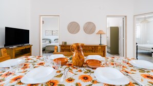 Een eetruimte met een tafel voor vier personen, een televisie en een karaf op tafel.